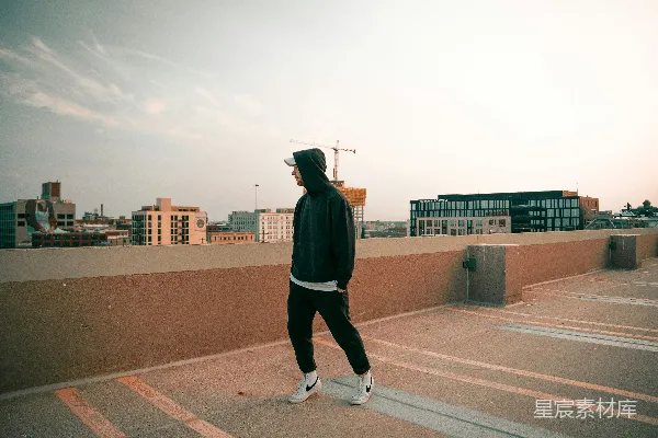 高清摄影 一个男人正走过停车场，旁边有一栋高楼。
