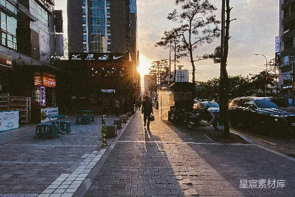 高清摄影 一个人在高楼大厦旁的人行道上行走。