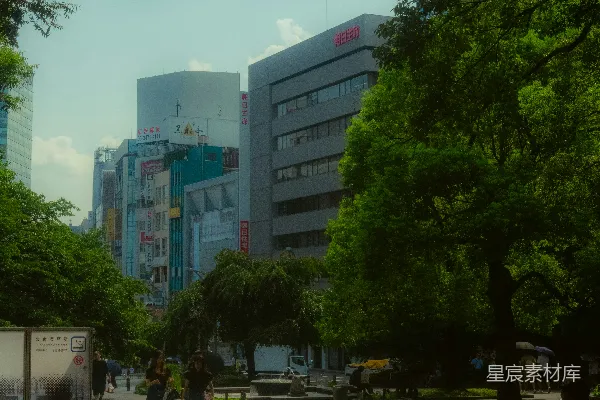 高清摄影 人们在公园里散步，背景是城市建筑。