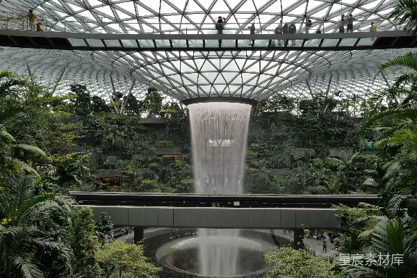 高清摄影 室内的瀑布，周围绿意盎然，搭配现代化的建筑结构。