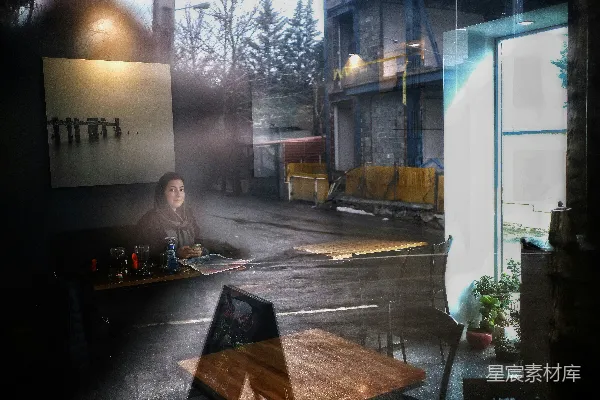 高清摄影 一位女士坐在窗前的桌子旁。
