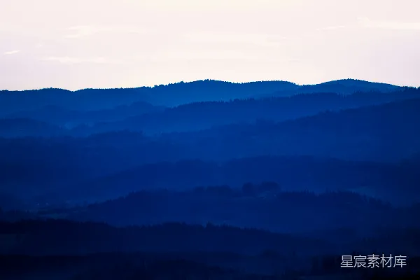 高清摄影 淡蓝色的天空下，山脉层层叠叠。