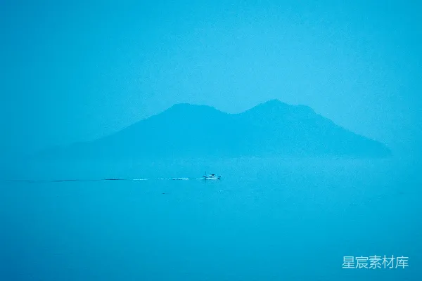 高清摄影 一座山的剪影映在蓝色的水面上。