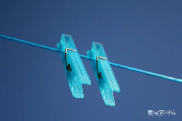 高清摄影 两个蓝色的塑料夹子挂在一条蓝色的晾衣绳上