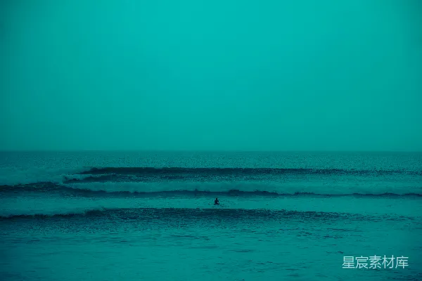 高清摄影 一个冲浪者坐在海里，被海浪包围着。