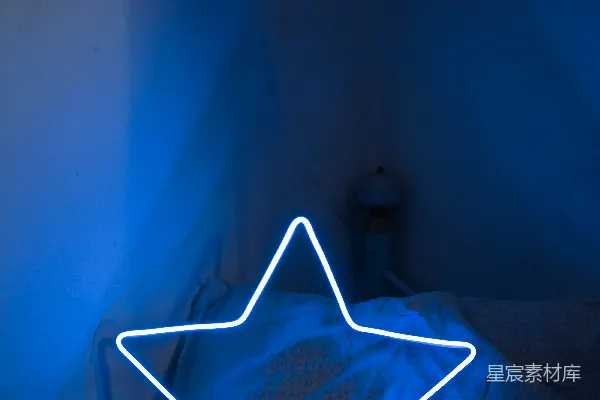 高清摄影 一张床上放着一个带星星形状的发光枕头。