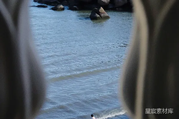高清摄影 人们在海浪和大岩石旁享受海滩。