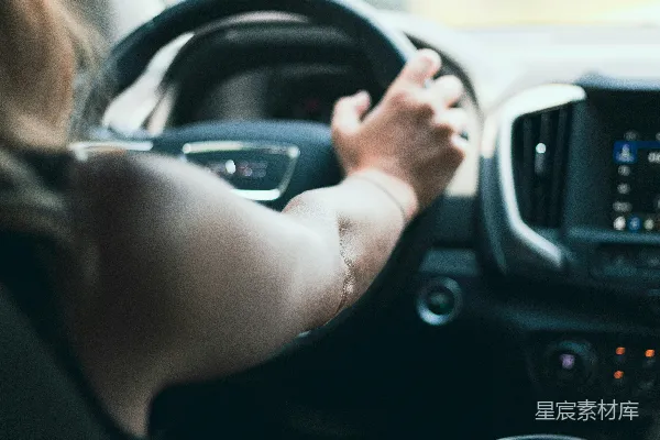 高清摄影 一个女人开着车，手放在方向盘上。