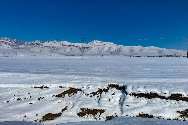 高清摄影 一片覆盖着积雪的田野，背景中是山脉。