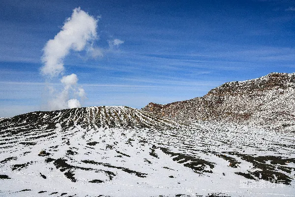 高清摄影 一座被雪覆盖的山峰，从它冒出一缕烟雾。
