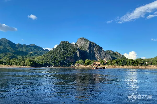 高清摄影 山峦俯瞰着一条宁静的河流，在一片明亮的蓝天之下。