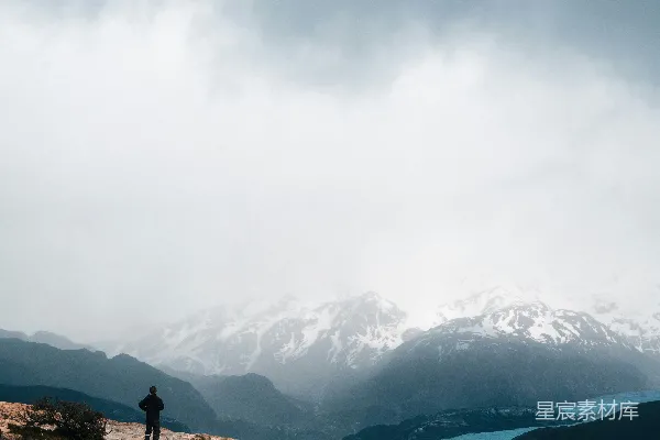 高清摄影 一个人站在山顶，旁边有一片水域。