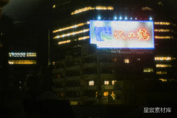 高清摄影 夜晚的城市，前景中有一个亮着的标志牌。