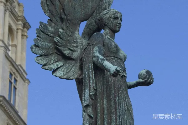 高清摄影 一座女人雕像，她手里拿着一只鸟，矗立在建筑物的顶部。