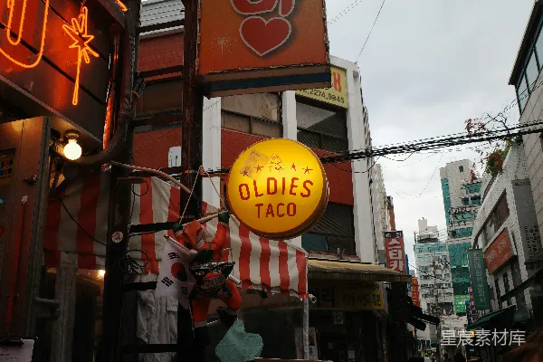 高清摄影 一个写着“老歌小吃卷饼”的招牌悬挂在城市街道上。