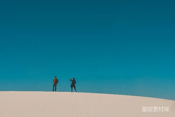 高清摄影 两个人在白天的沙丘上行走。