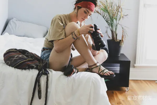 高清摄影 一位女士坐在床上使用相机。