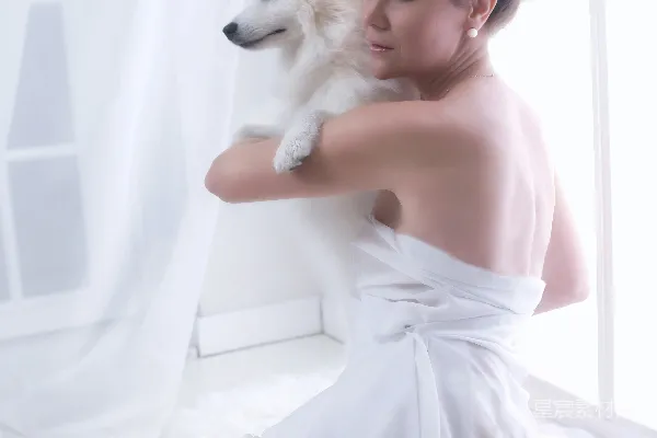 高清摄影 一位穿着白色连衣裙的女士抱着一只白色的狗。