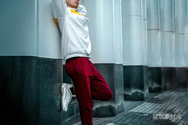 高清摄影 穿着白色长袖衬衫和红色裤子的男人靠在墙上。