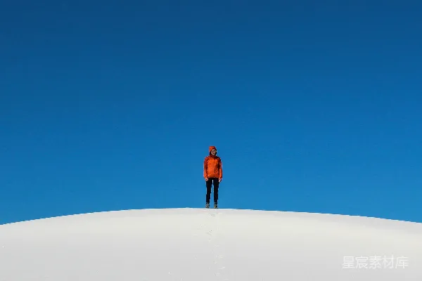 高清摄影 穿着橙色夹克的男人站在白天的白色沙滩上。