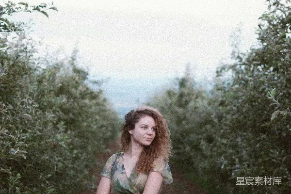 高清摄影 穿红白格子连衣裙的女人站在白天的绿色草地上。