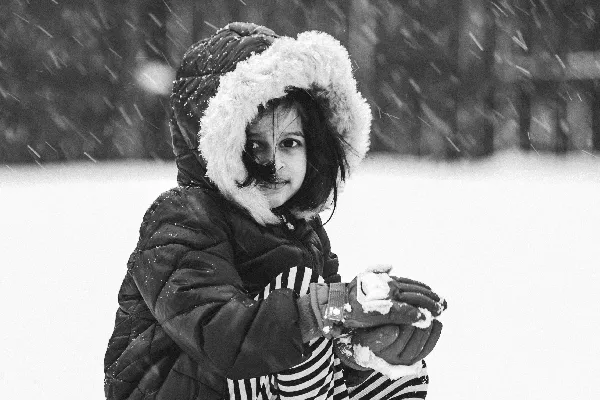 高清摄影 一个小女孩戴着帽子坐在雪地里。