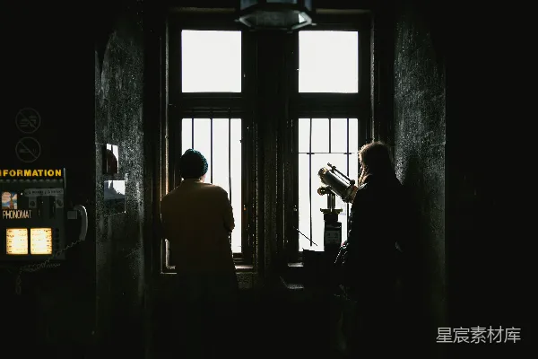 高清摄影 两个人从带铁栏的窗户向外看。