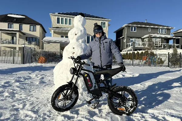 高清摄影 一个男人站在雪人旁边，旁边还有一辆自行车。