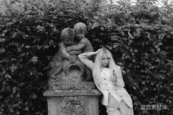 高清摄影 女人站在花园里的一尊雕像旁边。