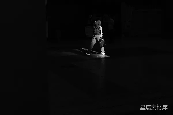 高清摄影 一个人在昏暗的街道上走在聚光灯下。