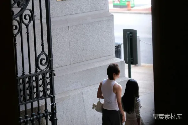 高清摄影 两个人走过一座装饰华丽的大门的建筑旁。