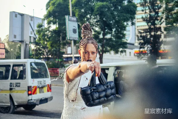 高清摄影 一个穿着白色连衣裙的女人手里拿着一个黑色的手提包。