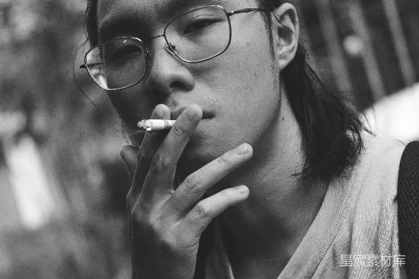 高清摄影 戴眼镜的男人在街上吸烟。