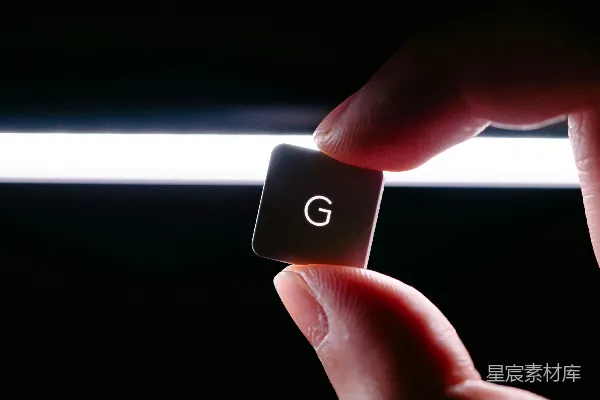 高清摄影 一只手拿着一个黑色的正方形物体，上面有字母"g"。