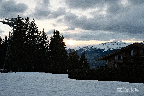 高清摄影 雪景中的山景，夕阳下有一所房屋。