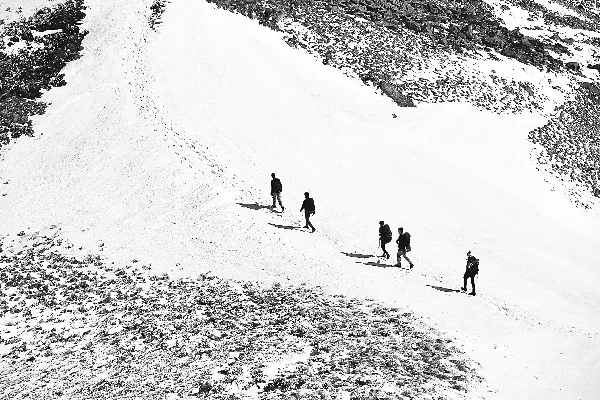 高清摄影 一群人正在攀登被雪覆盖的山的一侧。