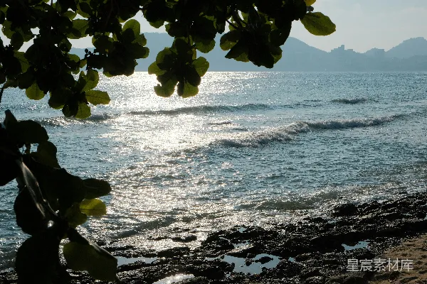 高清摄影 阳光在岸边岩石旁的海浪上闪烁。