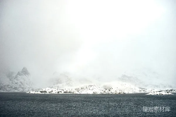 高清摄影 覆盖着积雪的山脉在黑暗的水域上笼罩着薄雾