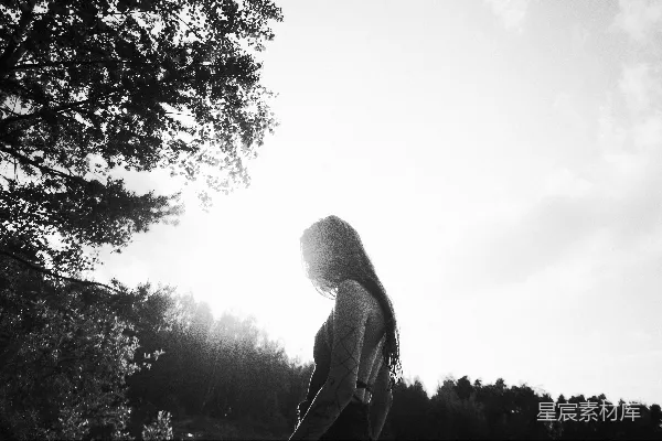 高清摄影 一个女人站在田野里，背景中有树木。