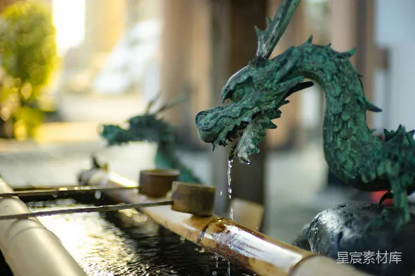 高清摄影 一张水泉的特写，背景中有一座龙雕像。