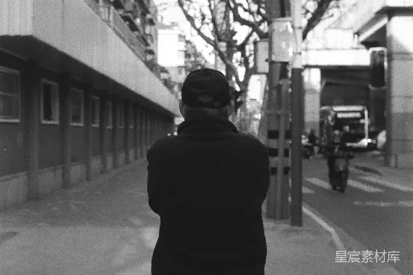 高清摄影 一个人靠在城市街道上的柱子上。