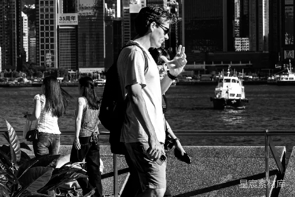 高清摄影 人们沿着水边漫步，城市天际线在背景中。