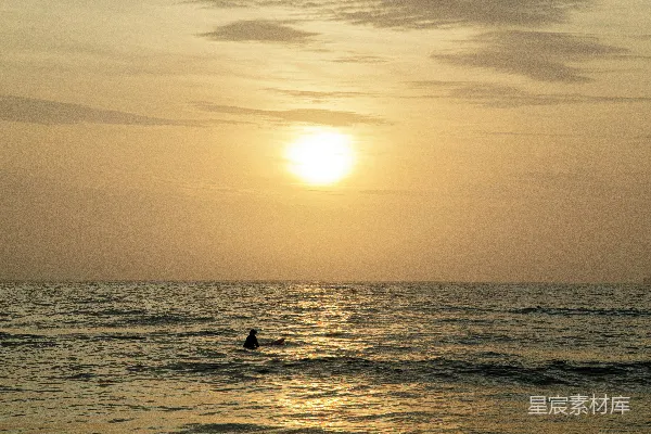 高清摄影 夕阳西下，一个人在海中冲浪。