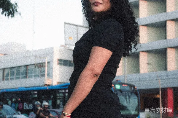 高清摄影 一位穿着黑色短裙的女士站在人行道上。