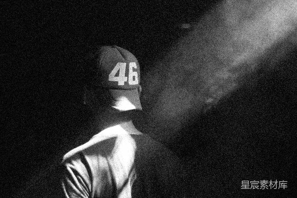 高清摄影 一个戴着棒球帽的男人站在黑暗中