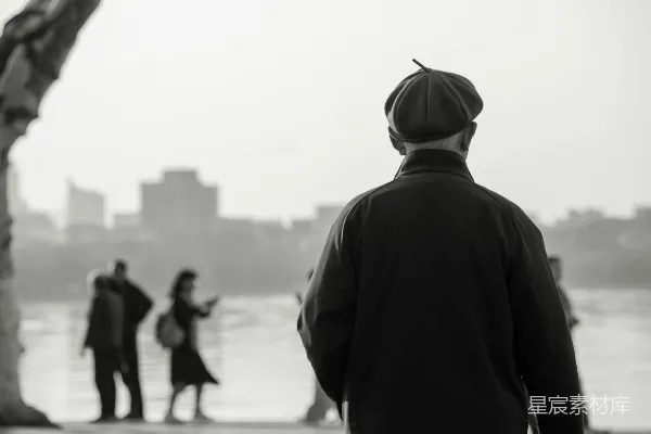 高清摄影 戴着帽子的男人背对着镜头，站在水边。