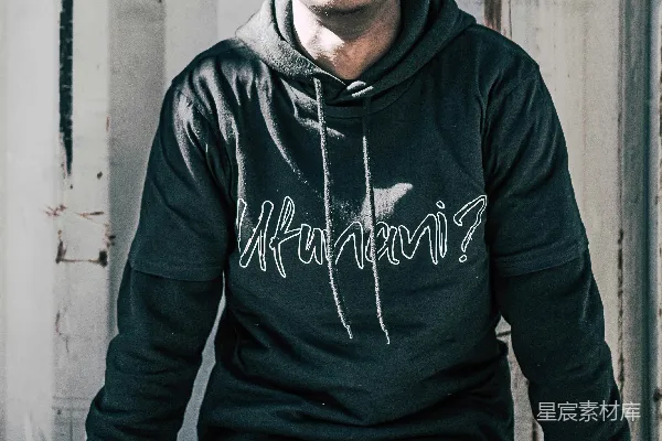 高清摄影 一个穿着黑色耐克连帽衫和蓝色牛仔裤的男人坐在白色的木制长凳上。
