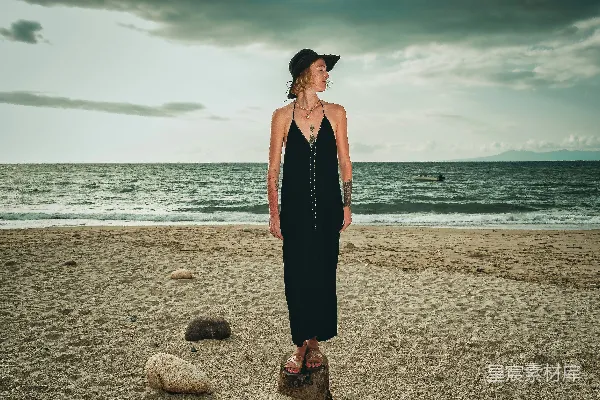 高清摄影 穿着黑色无肩带连衣裙的女子在白天的海滩上站着。