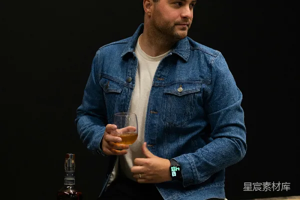 高清摄影 穿蓝色牛仔夹克的男人拿着一个透明的饮料杯