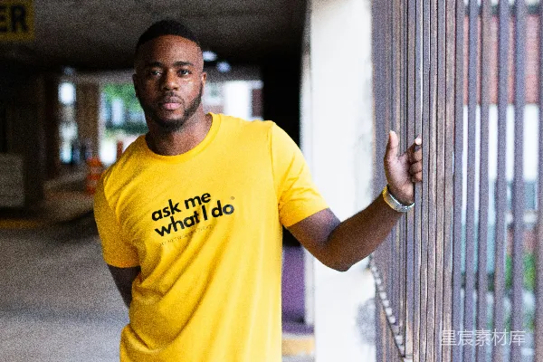 高清摄影 穿着黄色圆领T恤的男人靠在白墙上